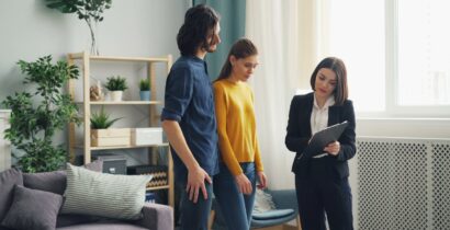 Real estate agent consulting a couple in a modern living room setting, surrounded by indoor plants.
