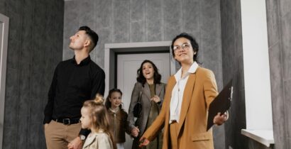 Happy family exploring a new home with a professional real estate agent guiding the tour. Dwellopolis.com