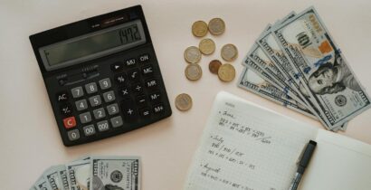 Flat lay of calculator, cash, coins, and handwritten notes for budget planning.