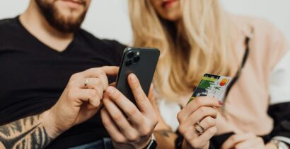 A couple using a smartphone and credit card for online shopping indoors.